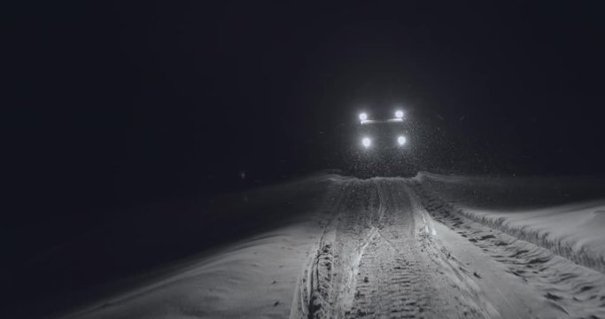 Half-track driving in the night in Jotunheimen in Norway. The half-track has skies in front. Its night and the snow are falling. Filmed on a gimbal in 4k. This is a slow-motion clip.