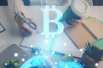 Cryptocurrency hologram, bitcoin, ico theme over hands taking notes background. Concept of blockchain. Multi exposure
