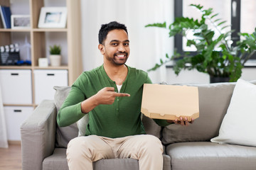 food delivery, consumption and people concept - smiling indian man with box of takeaway pizza at home