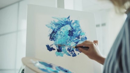 Zoom in shot of creative woman painting abstract picture on canvas with acrylic paints and palette knife