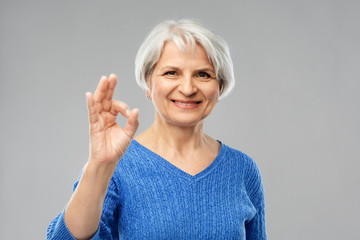 Obraz premium old people concept - portrait of smiling senior woman in blue sweater making ok gesture over grey background
