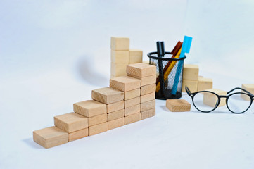 Wood block stacking as step stair on wooden table. Business concept for growth success process with color marker case and glasses