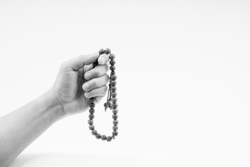 Hand holding a muslim rosary beads or Tasbih on black and white. Copy space and selective focus