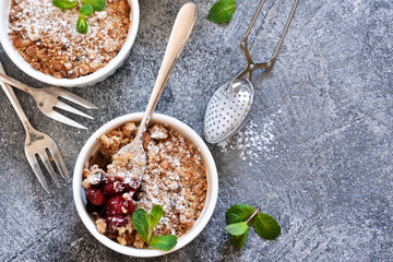 Cherry crumble with nuts and mint on a concrete background.