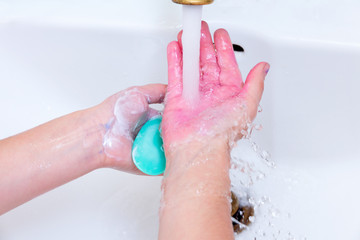 Fototapeta premium girl washes her hands in paint after drawing