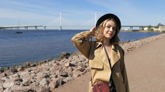 portrait of a stylish woman on the shoreline on the background of the bridge