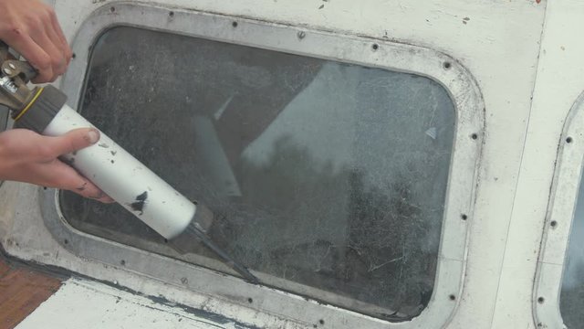 Sealing front windows on bow of wooden boat with sika flex mastic waterproof sealant