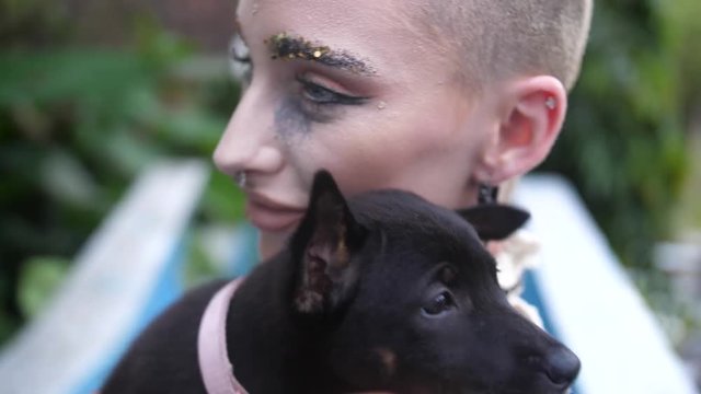 Calm small dog rests head on shoulder of woman holding it. Lady enjoying cuddling and kissing a young puppy as she holds it close.