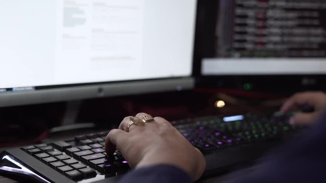 Close up on professional programmer coding, typing on rgb keyboard, potentially working on some kind of software in 4k.