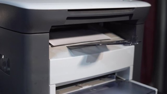 Close-up footage about an automatic printer while working/printing papers. 4K, close-up, office conception.