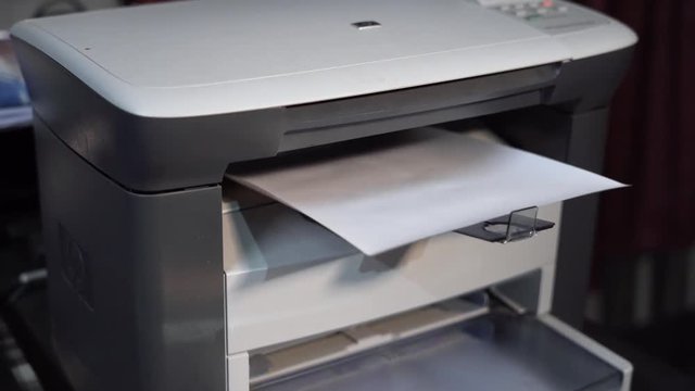An automatic modern printer is printing white papers in an office. 4K, close-up, job conception.