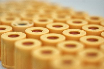 macro of test tubes with yellow top, against a gradient of white background. Selective focus