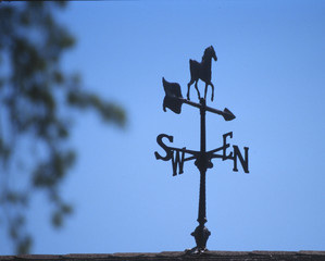 A weather vane highlighted against a blue sky.