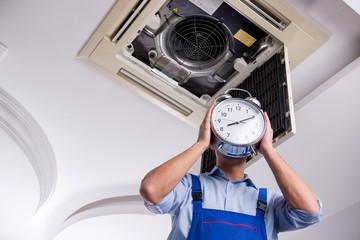 Young repairman repairing ceiling air conditioning unit 