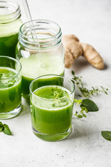 Green detox juice with ginger and mint in glasses and jars.