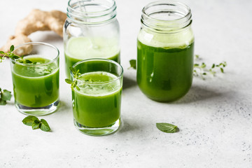 Green detox juice with ginger and mint in glasses and jars.