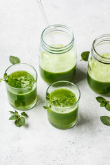 Green detox juice with ginger and mint in glasses and jars.