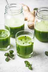 Green detox juice with ginger and mint in glasses and jars.