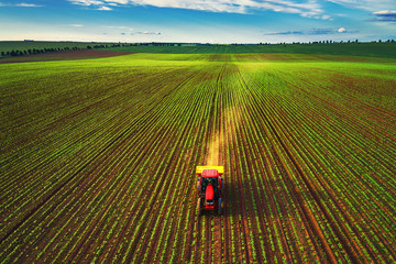 Tractor cultivating field at spring, aerial top drone view