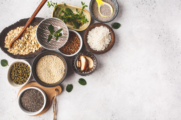 Food background - rice, chia seeds, nuts, oatmeal, buckwheat, quinoa, mung beans and greens on a white background.
