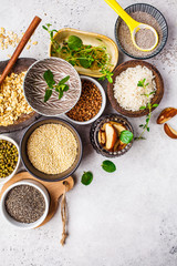 Food background - rice, chia seeds, nuts, oatmeal, buckwheat, quinoa, mung beans and greens on a white background.