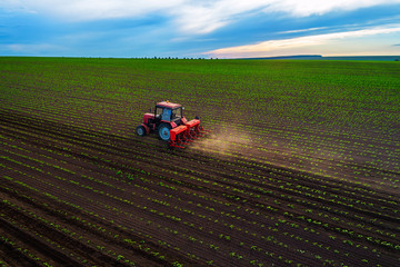 Tractor cultivating field at spring, aerial top drone view