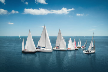 Regatta sailing ship yachts with white sails at opened sea. Aerial view of sailboat in windy...