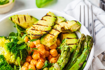 Buddha bowl with grilled avocado, asparagus, chickpeas, pea sprouts and broccoli.