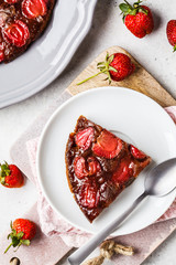 Slices of strawberry pie (tart) on black and white saucers, top view.