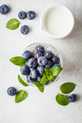 Chia pudding with blueberries and mint in glass on a white background, top view.