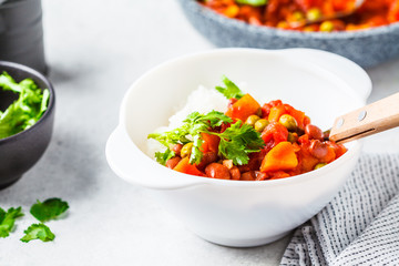 Vegan bean stew with tomatoes and rice in a pan over white background.