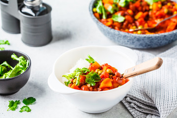 Vegan bean stew with tomatoes and rice in a pan over white background.