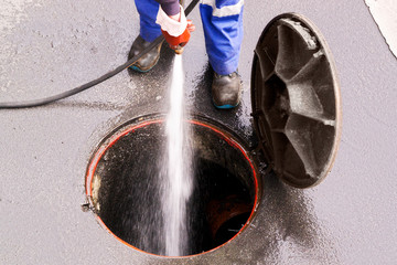 sewer line drainage  by utilities workers with hose with pressurized water of service truck