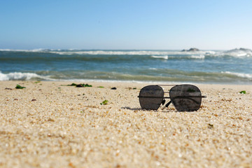 Dark sunglasses on the sandy beach in summer, low angle shot