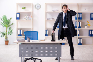 Young male employee in the office in time management concept 
