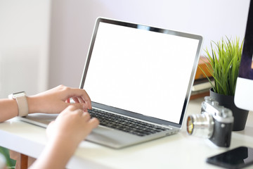 Female hand typing laptop showing blank screen  on table office place