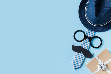 Fathers day concept with hat, glasses and tie on blue background - Powered by Adobe
