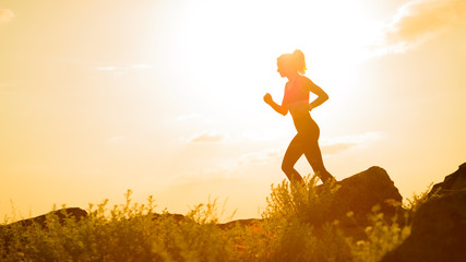 Young Beautiful Woman Running on the Mountain Trail at Hot Summer Sunset. Sport and Active Lifestyle.