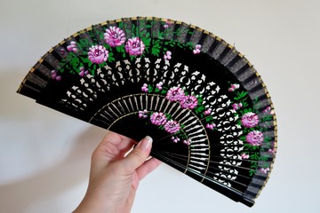 black fan with a pattern in hand on a light background