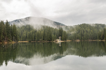 Mountain lake reserve Synevyr in the Carpathians, a rainy day with clouds in the trees