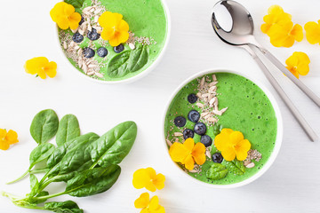green spinach smoothie bowl with blueberry, chia seed and edible pansy flowers