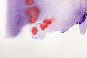 purple and red watercolor paint spills on white background