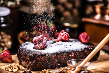 Brownie in chocolate syrup with strawberries. Sugar snow