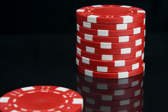 stack of red casino chips on black background with reflection