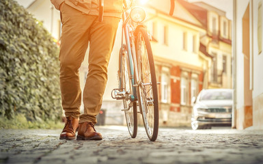 Naklejka premium Young stylish businessmango to work on his sport retro bike in s
