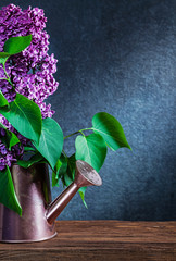 vertical view lilac flowers in bronze watering can on black background
