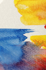 close up view of yellow, blue and red watercolor paint brushstrokes on white background