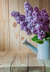 vertical view flowers of lilac in white watering can on wood
