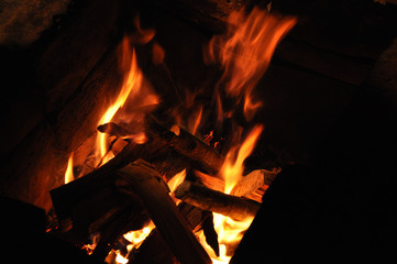 Burning wood campfire in the night darkness. Firewood bonfire is blazing. Abstract blurred flame background. Fiery backdrop.