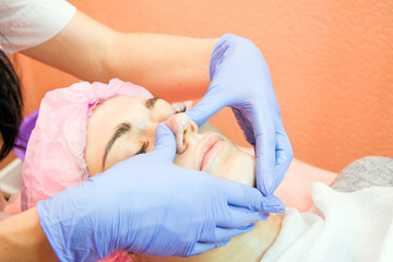 experienced cosmetologist applies a mask of emulsion